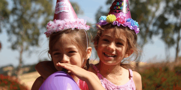 Two young girls wearing birthday hats